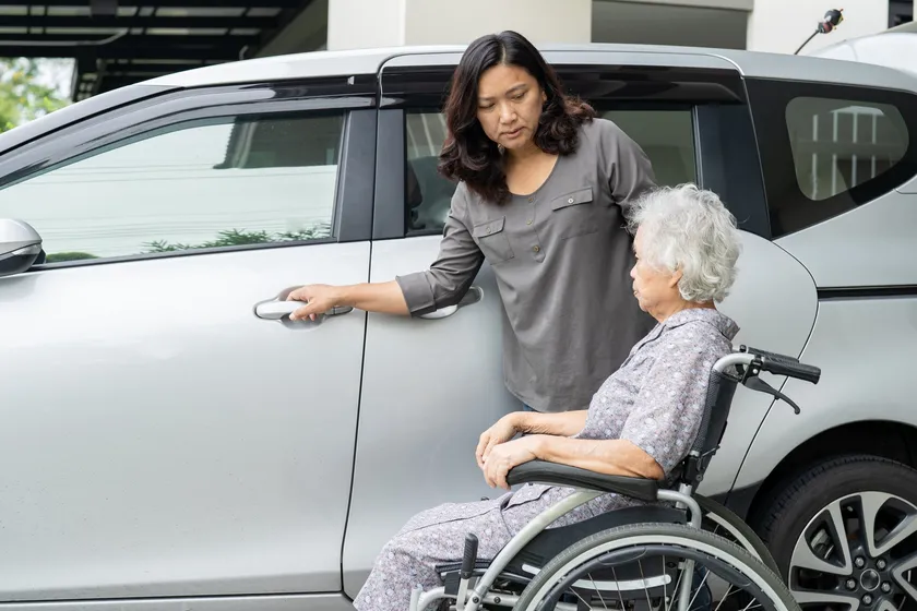 Aide à une personne aînée près d’un véhicule
